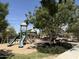 Community playground with slides, climbing structures, and mature shade trees at 14793 W Surrey Dr, Surprise, AZ 85379