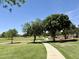 Concrete walking path through a lush green community park with mature trees and landscaping at 14793 W Surrey Dr, Surprise, AZ 85379