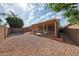 Gravel-covered backyard featuring a covered patio and brick-lined accents, offering a low-maintenance outdoor space at 15025 W Bottle Tree Ave, Surprise, AZ 85374