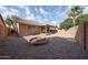 This spacious backyard features low-maintenance gravel, a brick fire pit, covered patio, and block fence at 15025 W Bottle Tree Ave, Surprise, AZ 85374