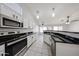 Bright kitchen featuring white cabinets, black countertops, stainless appliances, and a view to the living space at 15025 W Bottle Tree Ave, Surprise, AZ 85374