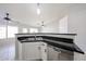 Kitchen island with stainless steel sink and dishwasher, with white cabinets and dark countertops at 15025 W Bottle Tree Ave, Surprise, AZ 85374