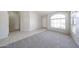 Bright living room featuring neutral carpet, white walls, tile entry, and arched windows at 15025 W Bottle Tree Ave, Surprise, AZ 85374