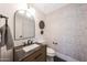 The powder room features modern wallpaper, wood vanity with marble countertop at 16008 N 60Th St, Scottsdale, AZ 85254