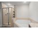 Bright bathroom features a glass shower and tub with tan tile surround at 17 W Vernon Ave # 412, Phoenix, AZ 85003