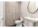 Modern powder room with gray tile accent wall and floating pedestal sink, complemented by sleek fixtures at 1704 E Melrose St, Mesa, AZ 85203