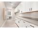 Spacious laundry room with white cabinets, quartz countertops, utility sink, and modern fixtures at 1704 E Melrose St, Mesa, AZ 85203