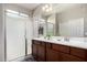 Well-lit bathroom featuring double vanities, a framed mirror, and a glass-enclosed shower at 18076 W Redwood Ln, Goodyear, AZ 85338