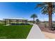 Inviting community space showcasing a covered picnic area, smooth walking path, and vibrant green landscape with mature trees at 18076 W Redwood Ln, Goodyear, AZ 85338