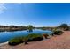 Breathtaking view of the community pond with walking path, blue skies and lush landscaping, offering a serene atmosphere at 18076 W Redwood Ln, Goodyear, AZ 85338