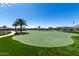 Beautifully landscaped putting green area surrounded by lush grass, palm trees, and a serene walking path, ideal for leisure at 18076 W Redwood Ln, Goodyear, AZ 85338