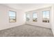 A bright bedroom features three large windows and plush gray carpeting at 18189 W Hess St, Goodyear, AZ 85338