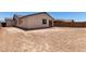 A spacious backyard features a dirt ground with the home's rear elevation visible under a clear blue sky at 18204 W Hess St, Goodyear, AZ 85338
