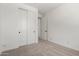 Bedroom with neutral carpet and closet featuring folding doors and an open bathroom at 18204 W Hess St, Goodyear, AZ 85338