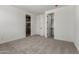 A light bedroom with neutral carpet and doors leading to a closet and bathroom at 18204 W Hess St, Goodyear, AZ 85338