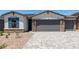 A two-car garage features stone accents and desert landscaping with a paved driveway leading up to it at 18204 W Hess St, Goodyear, AZ 85338