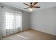 Neutral bedroom featuring a ceiling fan and bright natural light streaming through patterned curtains at 19820 E Reins Rd, Queen Creek, AZ 85142