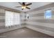 Stylish bedroom with horizontal striped walls, a modern ceiling fan, and sheer curtains, offering comfort and style at 19820 E Reins Rd, Queen Creek, AZ 85142