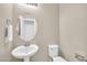 Well-lit half bathroom featuring a pedestal sink, oval mirror, and toilet at 2049 N 77Th Dr, Phoenix, AZ 85035