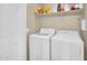 The laundry room includes a white washer, dryer and shelving unit with cleaning products at 2049 N 77Th Dr, Phoenix, AZ 85035