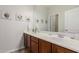 Bathroom with double sink vanity, tile floors, large mirror, and decorative floral prints on wall at 27289 N 90Th Ave, Peoria, AZ 85383