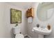 Cozy powder room featuring a pedestal sink, decorative wall art, and a wooden cabinet for storage at 27289 N 90Th Ave, Peoria, AZ 85383