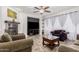 Cozy living room featuring a fireplace, ceiling fan, and plush sofas with a dark accent wall at 27289 N 90Th Ave, Peoria, AZ 85383