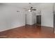 An empty living room with hardwood floors, a gray ceiling fan, and access to the front door, ready for furnishings at 3106 S Extension Rd, Mesa, AZ 85210