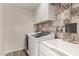 Laundry room features white cabinets, decorative backsplash, and a utility sink at 3255 E Malapai Dr, Phoenix, AZ 85028