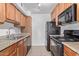 Galley kitchen with wood cabinets, granite countertops, and black appliances at 3500 N Hayden Rd # 1603, Scottsdale, AZ 85251
