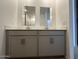 Double vanity bathroom with framed mirrors, sleek fixtures, and gray cabinets providing ample storage at 46922 W Coe St, Maricopa, AZ 85139