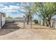 Backyard is enclosed by a chain-link fence and features a mature tree and shaded area at 6701 W Monterey Way, Phoenix, AZ 85033