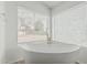 Bright bathroom features a freestanding tub with views of the backyard at 6701 W Monterey Way, Phoenix, AZ 85033