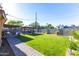 Lush backyard featuring a green lawn, brick walkway, and covered outdoor kitchen and dining at 8502 E Malcomb Dr, Scottsdale, AZ 85250