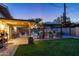 Lovely backyard features a pool, a covered patio with bar, a built-in barbecue grill and a lush lawn at 8502 E Malcomb Dr, Scottsdale, AZ 85250