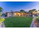 Expansive backyard with lush lawn, pool area, covered patio with bar, and a built-in barbecue grill at 8502 E Malcomb Dr, Scottsdale, AZ 85250