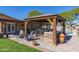Outdoor grill station under gazebo with stone accents, seating, and view of pool in backyard at 8502 E Malcomb Dr, Scottsdale, AZ 85250