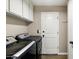 Well-lit laundry room featuring front-loading washer/dryer and white cabinets for ample storage space at 8502 E Rose Ln, Scottsdale, AZ 85250