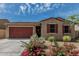 Charming single-story home featuring a red garage door, desert landscaping, and a cozy front porch at 8715 W Agora Ln, Tolleson, AZ 85353