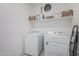 Efficient laundry room with modern white washer and dryer set and organized shelving at 8715 W Agora Ln, Tolleson, AZ 85353
