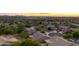 Aerial view of sunset, showcasing homes and neighborhood, with city lights in the distance at 10527 E Acacia Dr, Scottsdale, AZ 85255