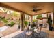 Inviting covered patio with a glass table, ceiling fan, and views of the landscaped backyard at 10527 E Acacia Dr, Scottsdale, AZ 85255