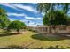 Lush green backyard with mature trees, a well-maintained lawn, and screened-in porch at 10860 W Cheryl Dr, Sun City, AZ 85351