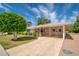 Charming home with a covered parking area, green lawn, and well manicured landscaping at 10860 W Cheryl Dr, Sun City, AZ 85351