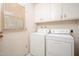 Bright laundry room features modern washer and dryer, white cabinets, and window at 10860 W Cheryl Dr, Sun City, AZ 85351