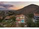 Aerial view showcasing a home with a sparkling pool against a backdrop of desert mountains at sunset at 1221 E Claire Dr, Phoenix, AZ 85022