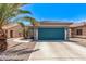 Attached garage with concrete driveway, desert landscaping and a well-maintained colorful blue door at 12913 W Columbine Dr, El Mirage, AZ 85335
