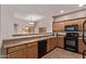 Well-lit kitchen with sleek black appliances, tile floors, and wood cabinets at 12913 W Columbine Dr, El Mirage, AZ 85335