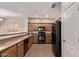 Well-lit kitchen with sleek black appliances, tile floors, and wood cabinets at 12913 W Columbine Dr, El Mirage, AZ 85335
