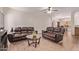 Spacious living room with two brown leather couches, glass table, ceiling fan, and tile floors at 12913 W Columbine Dr, El Mirage, AZ 85335